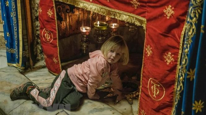 Một du khách nhỏ tuổi thăm hang đá, nơi tương truyền Chúa Jesus được sinh ra. (Ảnh: Quang Minh/TTXVN)