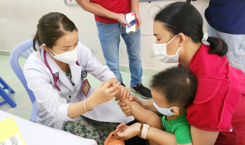 Một bệnh nhi được bác sĩ Bệnh viện Nhi Đồng 2 (Thành phố Hồ Chí Minh) khám bệnh tay-chân-miệng. Ảnh: PHẠM AN