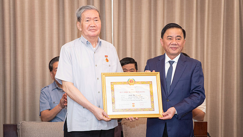 Đồng chí Trần Cẩm Tú trao Quyết định tặng Huy hiệu 50 tuổi Đảng cho đồng chí Đinh Thế Huynh. (Ảnh: SƠN TÙNG)