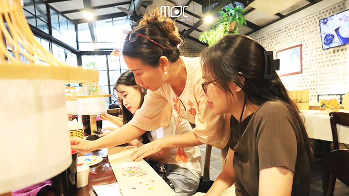 Chị Hữu hướng dẫn các thành viên làm đèn bàn. Ảnh: MOC