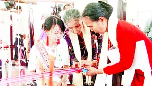 Nghệ nhân Đạt Thị Nam (áo cam) truyền dạy kỹ thuật dệt hoa văn Chăm cổ cho phụ nữ Chăm.