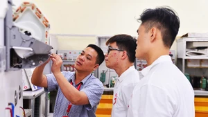 Quốc Khiêm (đeo kính, đứng giữa) trong giờ thực hành kỹ thuật máy lạnh.