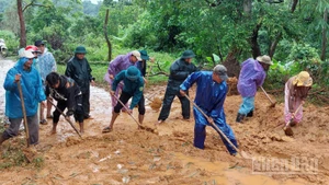 Bộ đội Biên phòng tỉnh cùng người dân dọn dẹp bùn đất trên các tuyến đường sau mưa lũ. 