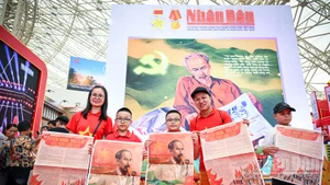 Niềm vui của một gia đình nhỏ khi xếp hàng và nhận được phụ san đặc biệt Báo Nhân Dân. Ảnh: THÀNH ĐẠT