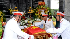 Các cựu chiến binh xã Thông Tân thực hiện nghi thức phủ Quân kỳ cho liệt sĩ Ngô Đức Mai. (Ảnh: THÀNH CHUNG)