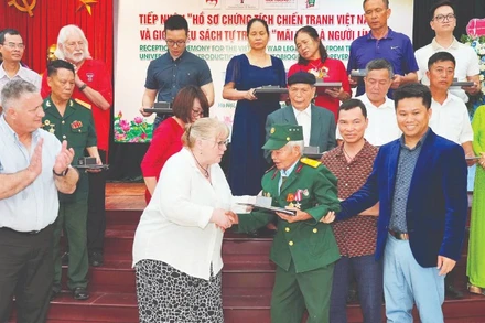 Đại diện Trường đại học Công nghệ Texas trao trả hồ sơ cho cựu chiến binh, thương binh Đỗ Xuân Thuyên.