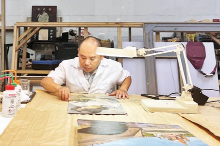 Ông Nguyễn Mạnh Hải làm sạch bức tranh của danh họa Trần Văn Cẩn.