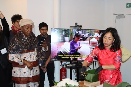 Chị Nguyễn Thị Liên, Việt kiều tại Brussels, giới thiệu cách gói bánh chưng. (Ảnh: HƯƠNG GIANG/TTXVN)