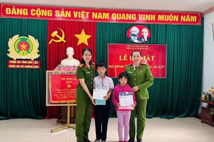 Đại diện Công an xã Krông Ana tặng quà cho con nuôi Đặng Hải Đăng và Hoàng Bảo Ngọc.