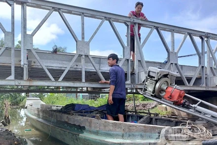 Một ghe tải phải chờ con nước xuống mới có thể đưa phương tiện vào ruộng muối vận chuyển hàng.