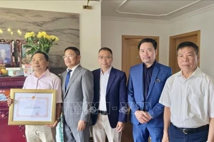 Tham tán Công sứ Chu Tuấn Đức (đứng giữa), Chủ tịch Hội Cựu chiến binh Việt Nam tại Cộng hòa liên bang Đức trao giấy khen, tri ân công lao của gia đình ông Lê Đình Bính có người thân là liệt sĩ. (Ảnh: PHƯƠNG HOA/PV TTXVN TẠI ĐỨC)