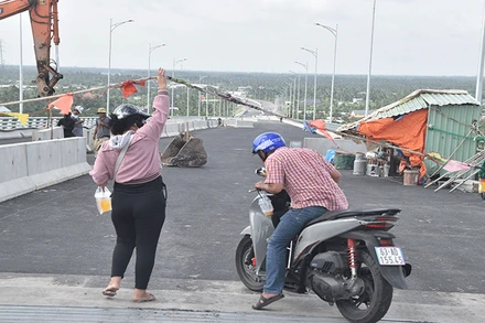 Người dân nâng dây để đi qua cầu Rạch Miễu 2.