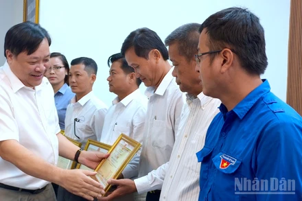 Chủ tịch Ủy ban nhân dân tỉnh Cà Mau Phạm Thành Ngại (bìa trái) tặng Bằng khen cho các cá nhân có nhiều đóng góp trong phong trào xóa nhà tạm, nhà dột nát.