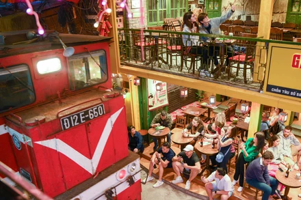 Khách du lịch ngồi sát khu vực đường ray khi tàu đi qua.