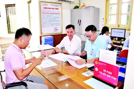 Cán bộ Trung tâm Phục vụ hành chính công phường Quảng Yên (tỉnh Quảng Ninh) hỗ trợ người dân làm thủ tục hành chính. (Ảnh QUANG THỌ)