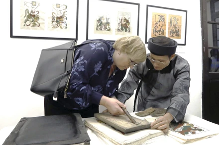 Nghệ nhân Nguyễn Hữu Quả giới thiệu kỹ thuật in tranh Đông Hồ tới du khách quốc tế, tại Bảo tàng Mỹ thuật Việt Nam.