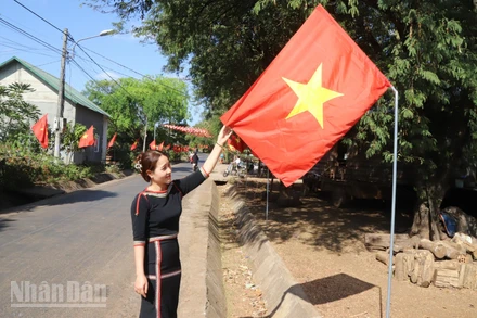 Bí thư Chi bộ buôn Tuôr, xã Hòa Phú H'Lin H'Đớt treo cờ Tổ quốc hướng về Đại hội XIV của Đảng.