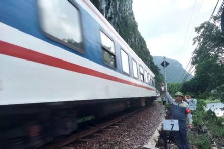 Nhân viên tuần hầm hướng dẫn tàu qua an toàn trên đoạn đường sắt xung yếu bên sông, bên núi đá ở huyện Tuyên Hóa, tỉnh Quảng Bình.