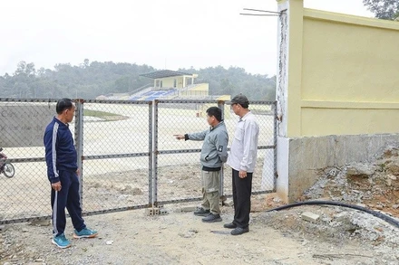 Ông Lò Văn Khăm (bên trái) cùng người dân trong bản Pú Tỉu 2 (phường Mường Thanh), chỉ cho phóng viên dấu tích con đường cũ về bản hiện là một góc trong sân vận động mới được đầu tư xây dựng hiện đại. 