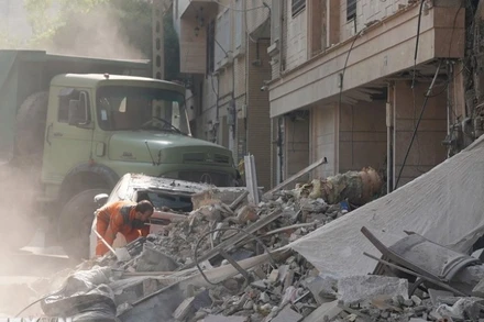 Nhân viên cứu hộ dọn đống đổ nát của tòa nhà bị sập tại Tehran, Iran sau các cuộc không kích của Israel. (Ảnh: THX/TTXVN)