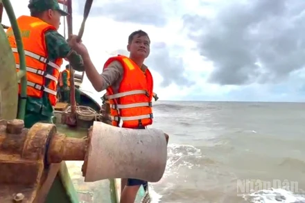 Một trong 2 thuyền viên (bìa phải) trên tàu cá gặp nạn được cán bộ, chiến sĩ Đồn Biên phòng Sông Đốc đưa lên tàu an toàn vào chiều muộn 29/9.