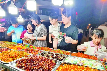 Du khách mua hàng tại một gian ẩm thực ở phố đi bộ Đinh Tiên Hoàng, phường Trần Lãm, tỉnh Hưng Yên.