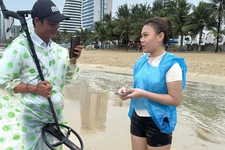 Nữ du khách nhận lại tài sản bị sóng biển nhấn chìm sau nỗ lực hỗ trợ, tìm kiếm của các nhân viên Ban Quản lý bán đảo Sơn Trà và các bãi biển du lịch Đà Nẵng. (Ảnh: HG)