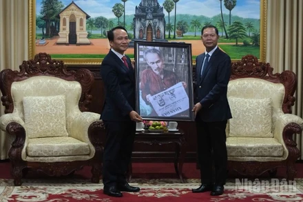 Phó Bí thư Thường trực Thành ủy Đà Nẵng Nguyễn Đình Vĩnh trao tặng bức ảnh Bác Hồ đọc Báo Nhân Dân cho lãnh đạo tỉnh Savannakhet. (Ảnh: ANH ĐÀO)