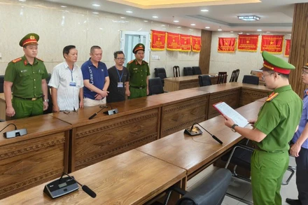 Cơ quan điều tra tống đạt các quyết định khởi tố đối với ba bị can. (Ảnh: Công an cung cấp)