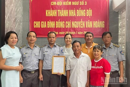 Đồng chí Vũ Văn Tài, Bí thư Đảng ủy Chi đội Kiểm ngư số 3 (thứ hai từ trái sang) trao kinh phí hỗ trợ nhà đồng đội cho gia đình đồng chí Nguyễn Văn Hoàng. (Ảnh: TIẾN DŨNG)