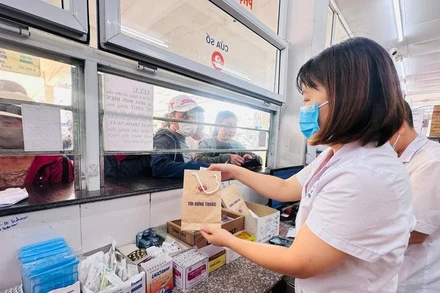 Nhân viên y tế cấp phát thuốc bảo hiểm y tế cho người bệnh. (Ảnh Thùy Giang)