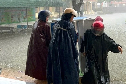 Giáo viên ở xã Quảng Trạch, Quảng Trị, di chuyển tài sản lên cao tránh hư hỏng khi nước lũ đã tràn vào sân trường hôm 31/10. (Ảnh: HƯƠNG GIANG)