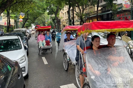 Du khách nước ngoài trên phố Tràng Thi (Hà Nội) ngày mưa. (Ảnh minh họa: Đ.T)