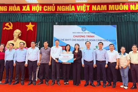 Trao biểu trưng tặng thẻ BHYT cho người dân.