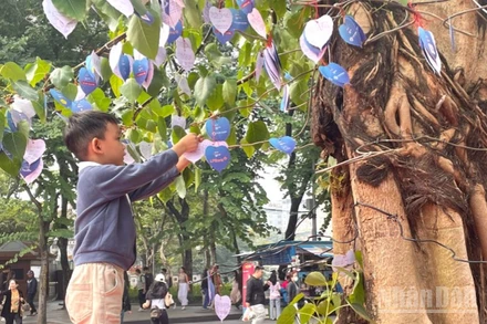 Em bé gửi gắm điều ước lên Cây Hạnh phúc. 