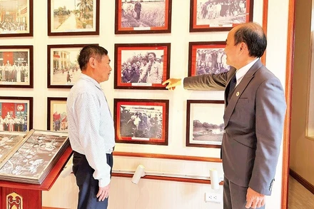 Ông Phùng Văn Tiệp (bên phải), Trưởng phòng Văn hóa-Xã hội xã Dân Hòa giới thiệu cho khách tham quan các hình ảnh về Chủ tịch Hồ Chí Minh tại Nhà lưu niệm Chủ tịch Hồ Chí Minh tại xã Dân Hòa.