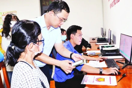 Cán bộ xã Long Thành hướng dẫn người dân nộp hồ sơ trực tuyến.
