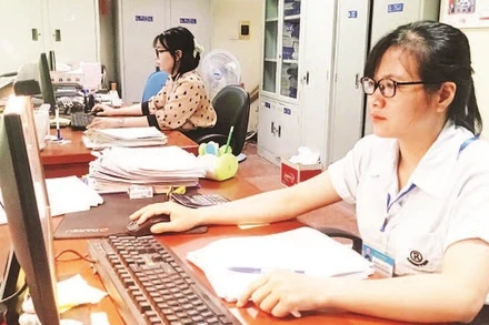 Cán bộ Đội Thuế thành phố Bắc Giang rà soát hồ sơ để thực hiện giảm tiền thuê đất cho doanh nghiệp. (Ảnh MINH LINH)