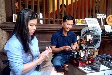 Khách tham quan tìm hiểu cách làm những chiếc dép cao-su mi-ni được dùng làm móc chìa khóa, quà tặng.