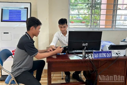 Cán bộ Trung tâm Phục vụ hành chính công xã Mỹ Lợi hướng dẫn người dân thao tác nộp hồ sơ trực tuyến. 