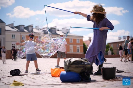 Trẻ em chơi với bong bóng xà phòng nổi tại Quảng trường Lâu đài Hoàng gia ở thủ đô Warsaw, Ba Lan. Các cơ quan khí tượng nước này đã ban hành cảnh báo nắng nóng đối với phần lớn đất nước trong tuần này. (Ảnh: Tân Hoa xã)