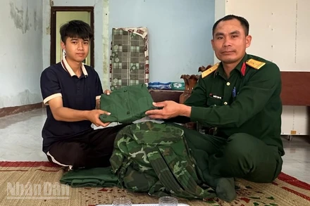 Thanh niên Vi Hồng Minh nhận quân phục mới từ cán bộ Ban chỉ huy Quân sự xã Ia Rvê.