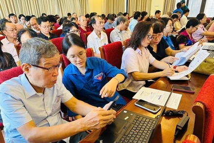 Đoàn viên thanh niên phường Văn Miếu-Quốc Tử Giám hỗ trợ các đảng viên thực hiện các thủ tục hành chính của Đảng trên Cổng dịch vụ công quốc gia. (Ảnh: BẢO LÂM). 