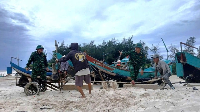 Cán bộ, chiến sĩ Đồn Biên phòng Roòn (Quảng Trị) giúp dân kéo, chuyển thuyền đánh cá lên bờ.