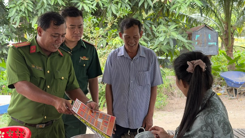 Trung tá Châu Văn Nát phát tờ rơi tuyên truyền cho người dân các phương thức tội phạm mới để nâng cao cảnh giác.