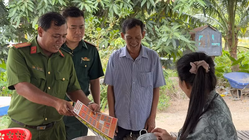 Trung tá Châu Văn Nát phát tờ rơi tuyên truyền cho người dân các phương thức tội phạm mới để nâng cao cảnh giác.