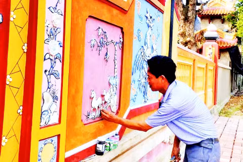 Nghệ nhân Đào Hữu Khiến thực hiện công đoạn khảm sành sứ trên bức bình phong tại Đại nội Huế.