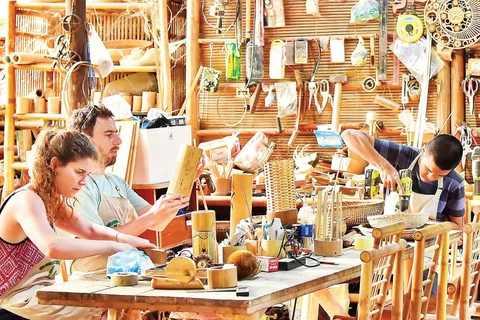 Du khách tự làm sản phẩm lưu niệm bằng tre tại một cơ sở thủ công mỹ nghệ ở Đà Nẵng. (Ảnh: MỸ HÀ)