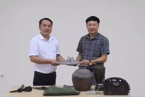 Phó Giám đốc Bảo tàng tỉnh Quảng Trị Mai Thế Trung (áo trắng) trao hiện vật, tư liệu phục vụ xây dựng Bảo tàng Đảng Cộng sản Việt Nam 
