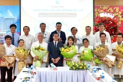 Thứ trưởng Y tế Trần Văn Thuấn tặng hoa và bằng khen cho ekip thực hiện ca can thiệp bào thai cho sản phụ người Singapore. (Ảnh: HOÀNG HÙNG)